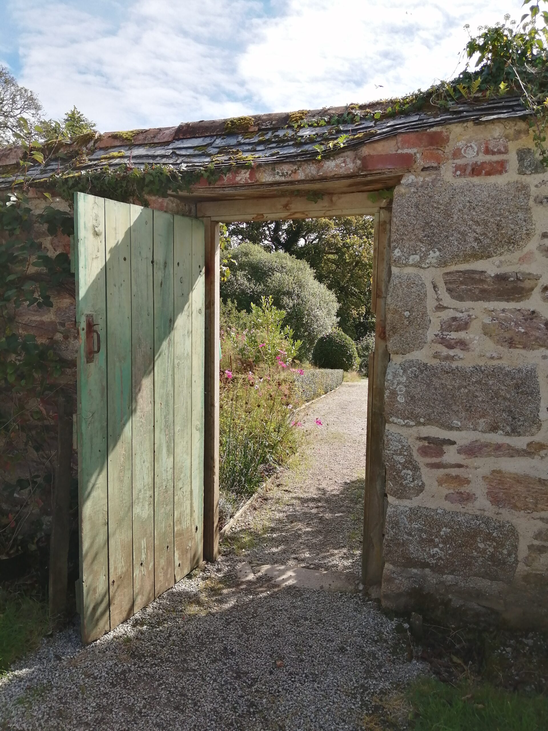 Wooden door in walled garden, open to reveal a view of the vegetable garden beyond